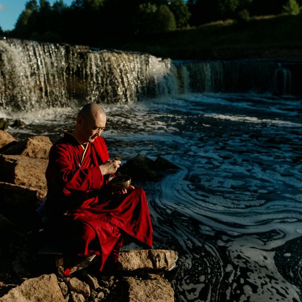 Person meditating in a serene environment with flowing energy lines.