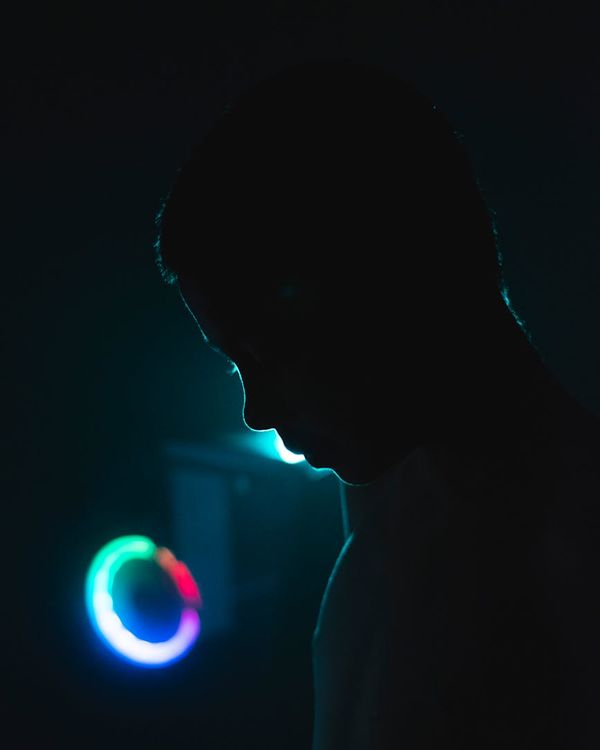 Woman in a calm yoga pose, outlined with cyan neon light.